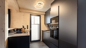A modern kitchen with wooden walls, a black countertop, and stainless steel appliances. - Chalet mit 4 Schlafzimmern, Sauna und Kamin (Biberwier)