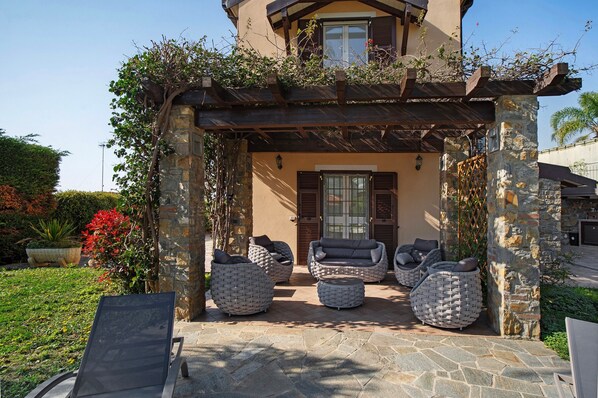 A stone building with a covered patio, outdoor seating, and a garden.