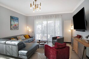 A modern living room with a grey sofa, red chair, and a flat-screen TV.