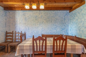 A dining area with a checkered tablecloth, wooden chairs, and a patterned wall. - Country House 'El Alarife' with Mountain Views, Wi-Fi, and Air Conditioning (Sediles)