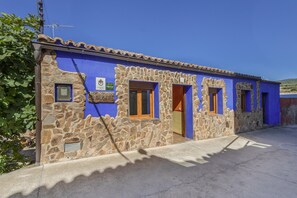 A building with stone walls and blue exterior, featuring multiple doors and windows. - Country House 'El Alarife' with Mountain Views, Wi-Fi, and Air Conditioning (Sediles)