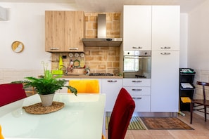 Una cocina compacta con gabinetes blancos, un salpicadero de ladrillo y una estufa moderna.