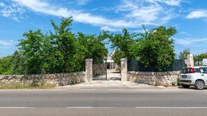 Une entrée fermée par un portail, avec des murs en pierre et un chemin pavé menant à un bâtiment.