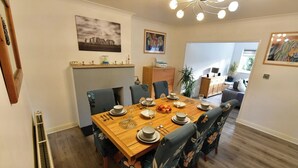 Comedor con mesa de madera dispuesta para seis personas, rodeada de sillas con estampado floral.