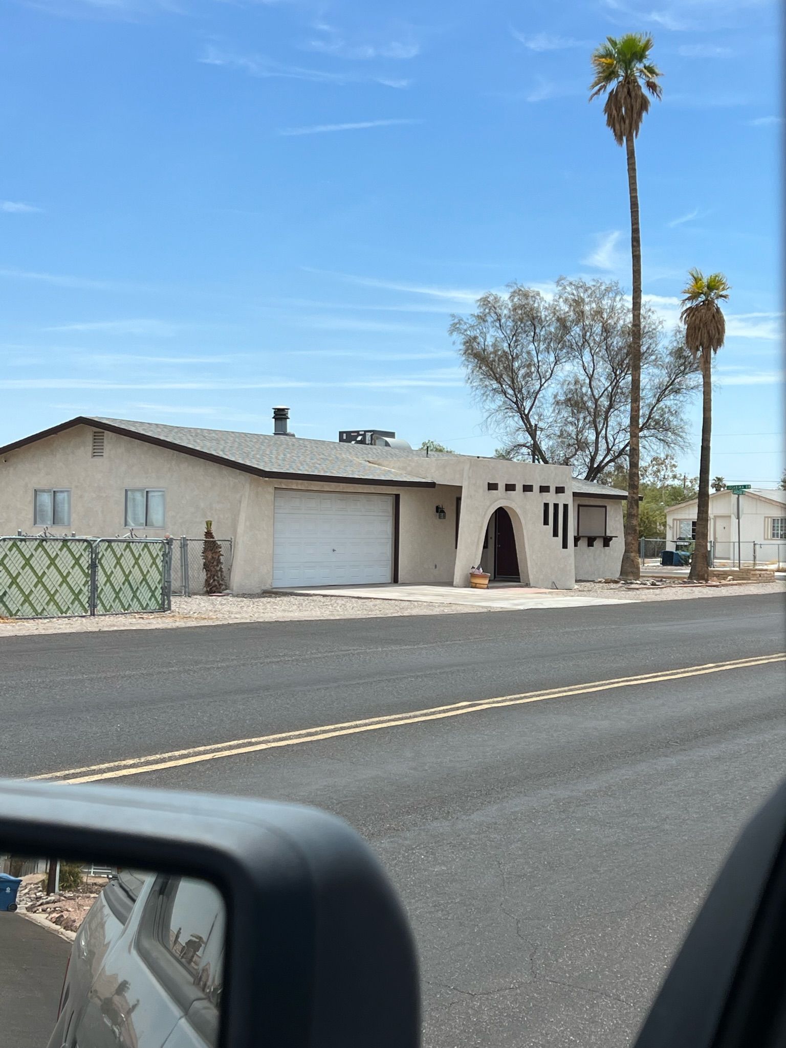 A single-story building with a garage, a small porch, and a palm tree in the background.