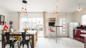 Une cuisine moderne avec un coin repas, de grandes fenêtres et une vue sur l’extérieur.
