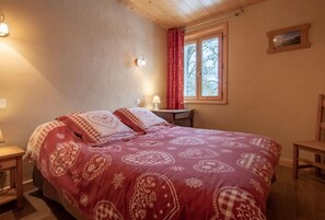 Un dormitorio con una cama grande, una mesita de noche, una lámpara, una ventana con cortinas y un cuadro en la pared.