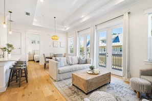 A spacious living area with a sofa, coffee table, and bar stools.