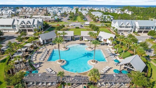 Um resort com piscina central, áreas de estar e vista para o oceano.