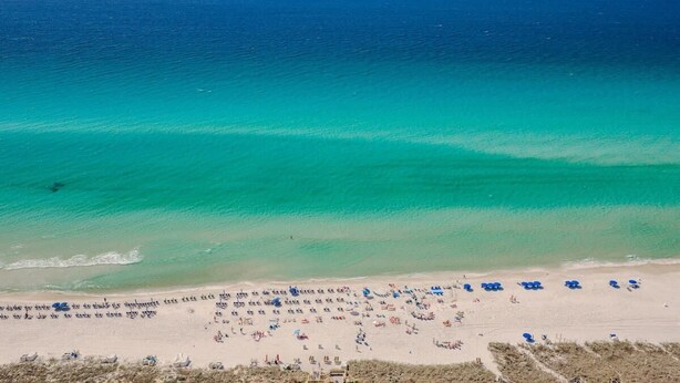 A beach with clear turquoise waters and a sandy shore.