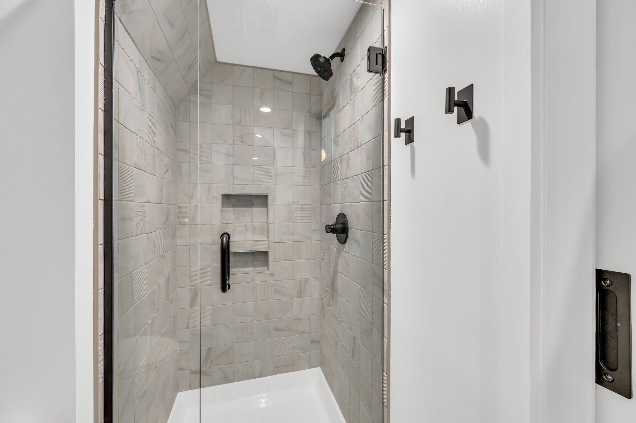 A modern bathroom with a glass shower enclosure, a white bathtub, and a wall-mounted towel rack.