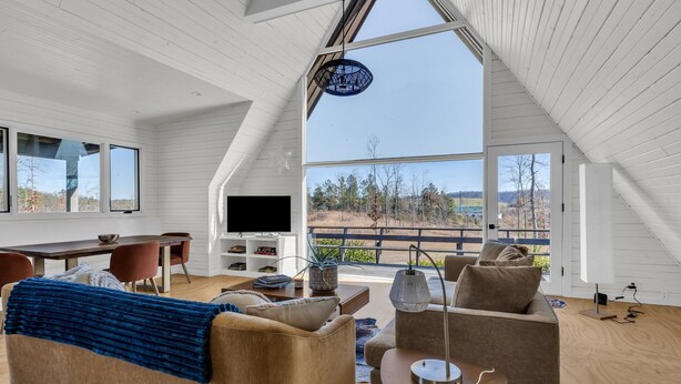 Una sala de estar moderna estilo loft, con un gran ventanal, televisor y comedor.