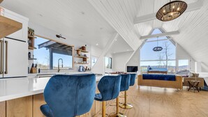 Cocina moderna con armarios blancos, una isla grande y taburetes azules.