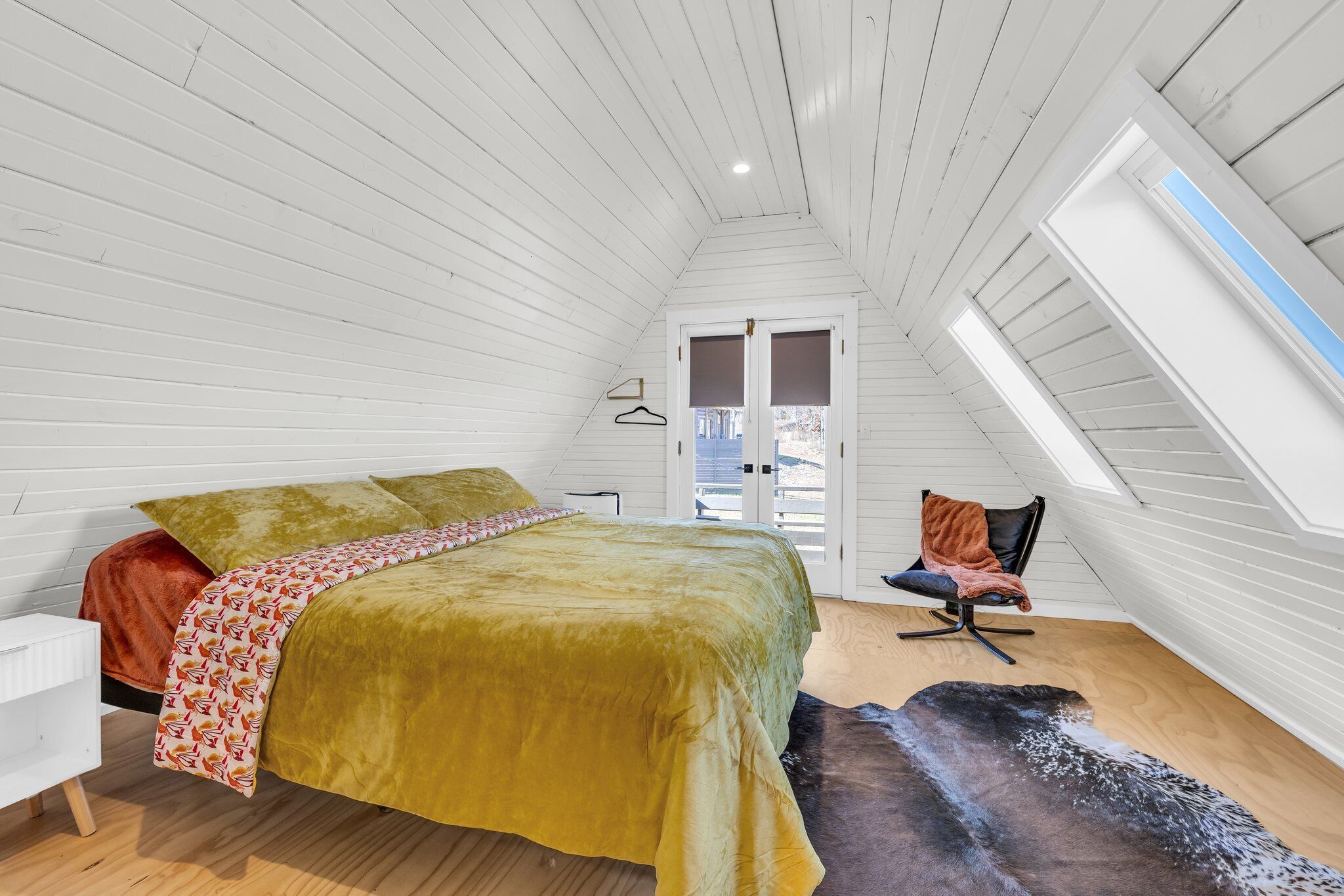 A bedroom with a bed, a chair, a window, and a door.