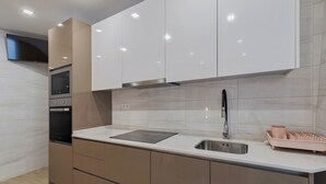 A modern kitchen with a built-in oven, microwave, and stainless steel sink. - Canto Doce Troino (Setúbal)
