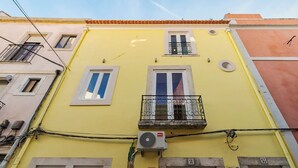 A yellow building with a balcony, a window, and a door. - Canto Doce Troino (Setúbal)