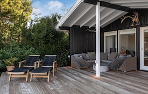 A covered outdoor seating area with lounge chairs and a sofa, surrounded by greenery. - Lovely summer house by Arresø (Hillerød)