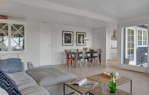 Una sala moderna con sofá, mesa de centro, comedor y ventanas amplias.