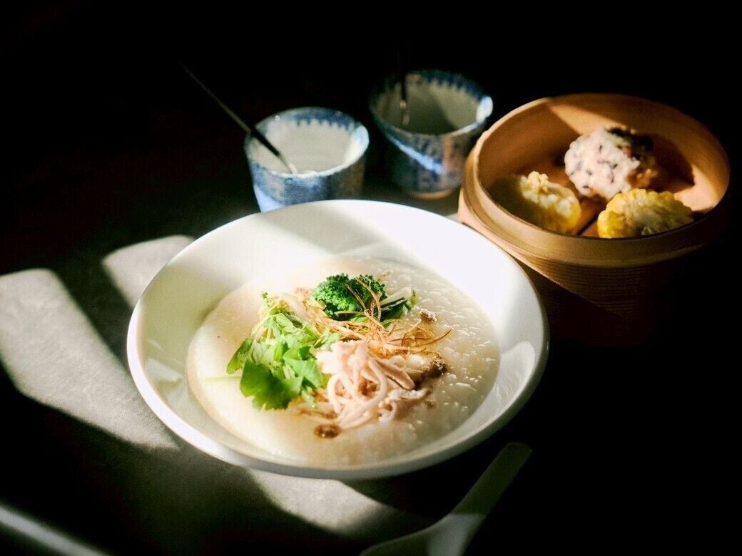 A bowl of soup with noodles and vegetables, accompanied by two small bowls of condiments.