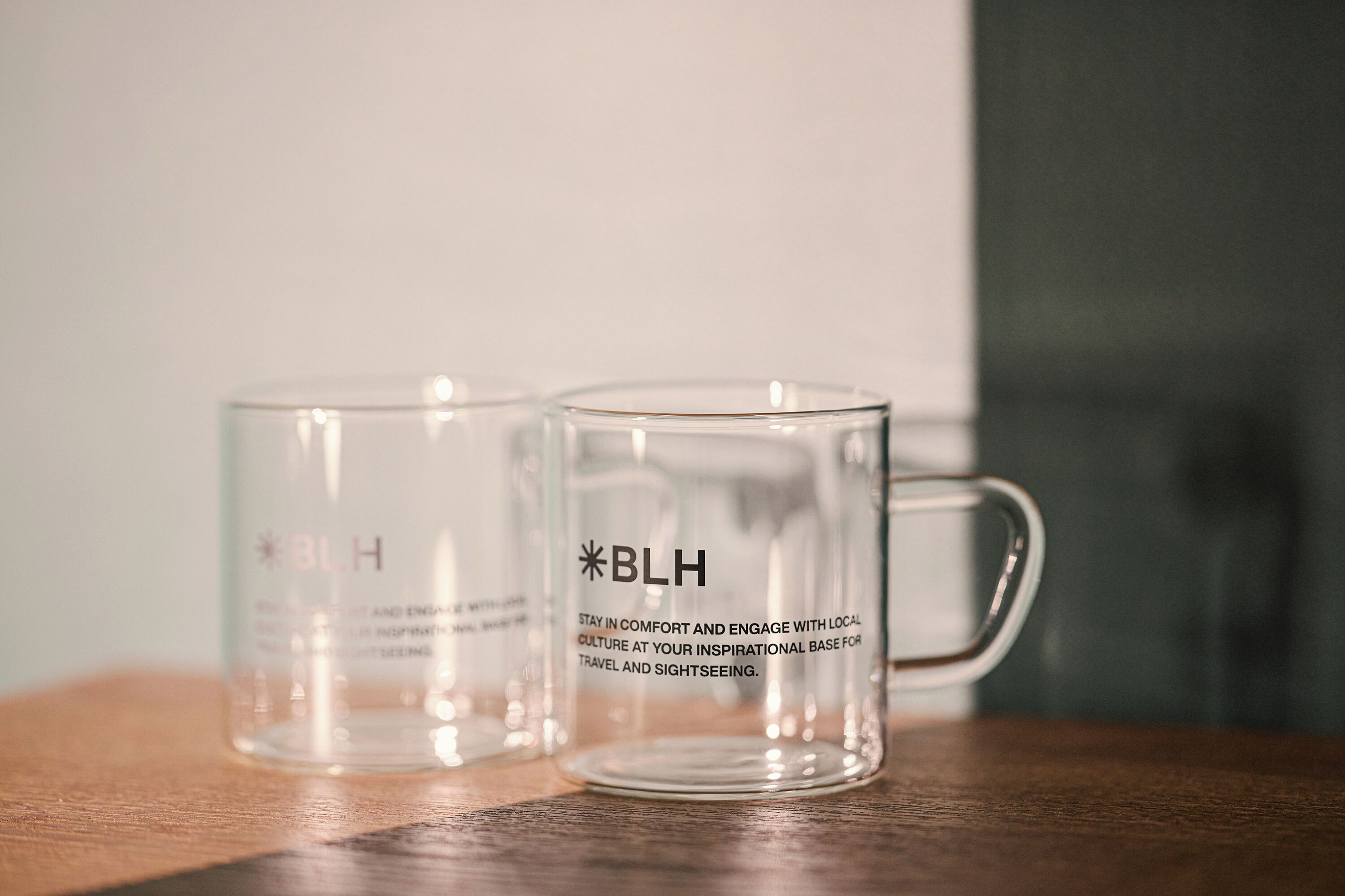Two clear glass mugs with the inscription "BLH" on a wooden surface.