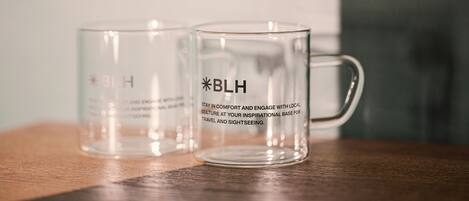 Dos tazas de vidrio transparente con la inscripción "BLH" sobre una superficie de madera.