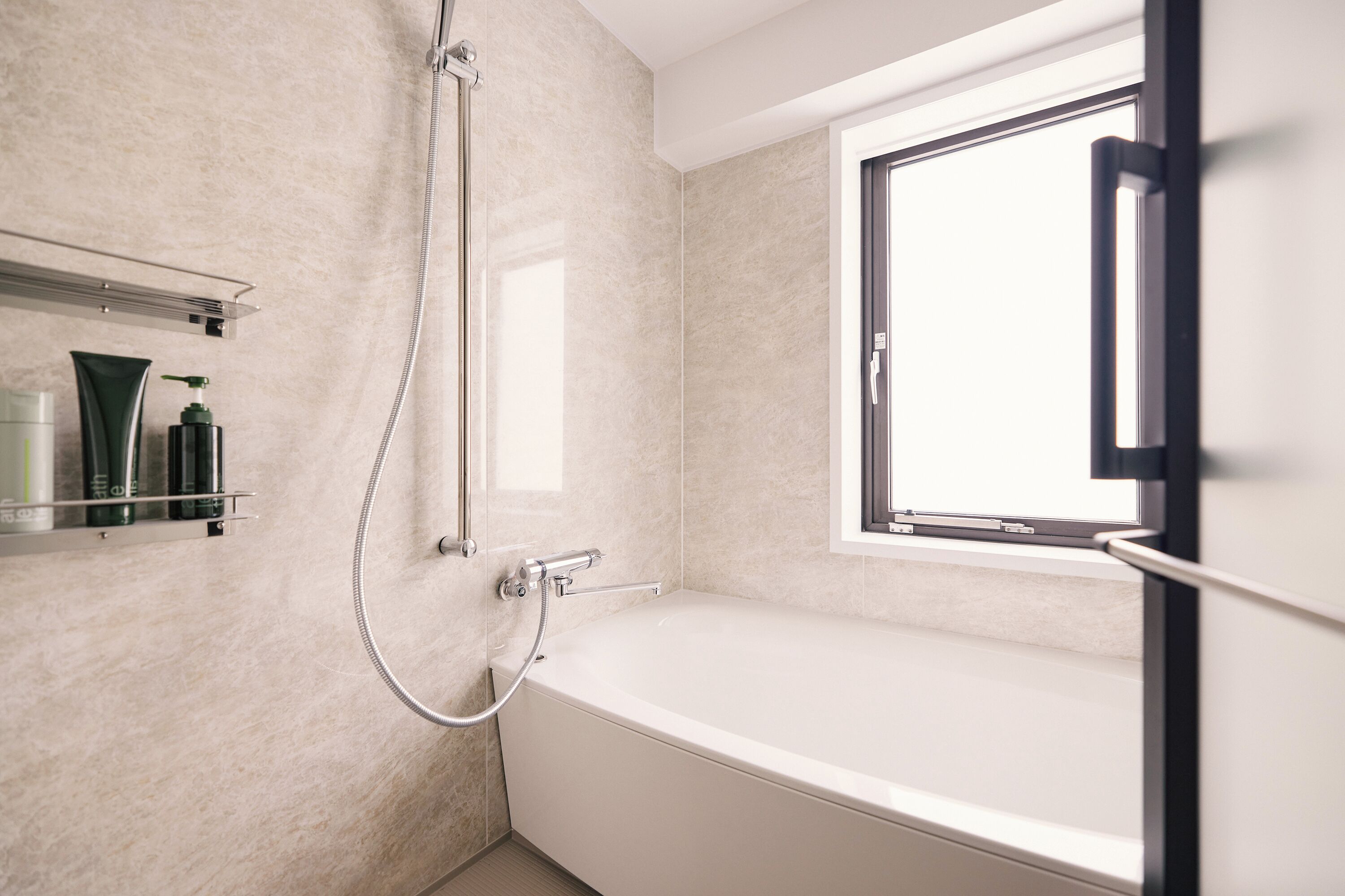 Un bagno moderno con vasca, doccia e una finestra che lascia entrare luce naturale.