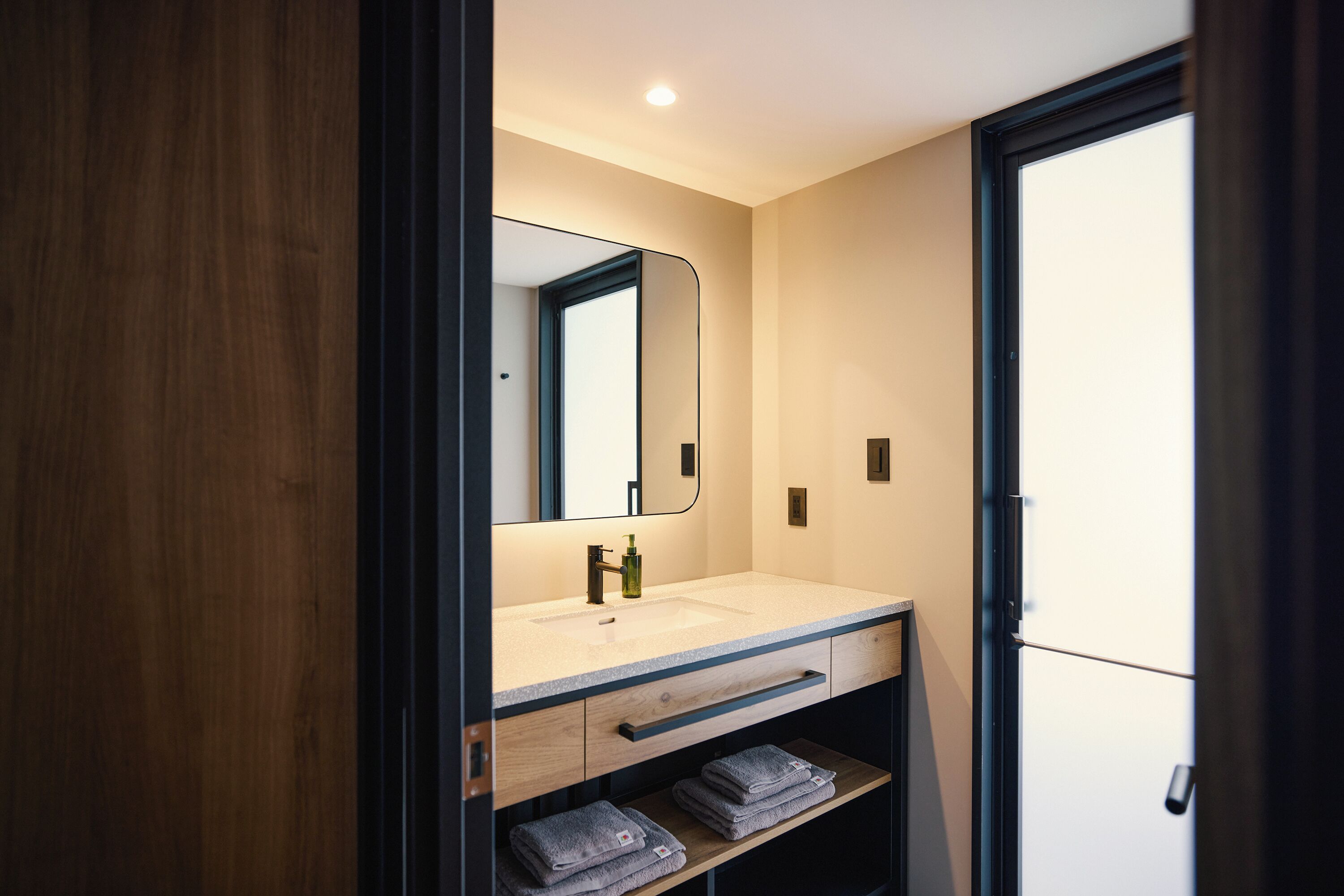 A modern bathroom with a wooden vanity, a mirror, a sink, and a towel rack.