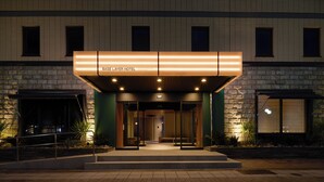 Entrada de hotel con diseño moderno, destacando una fachada de piedra y un área de acceso bien iluminada.
