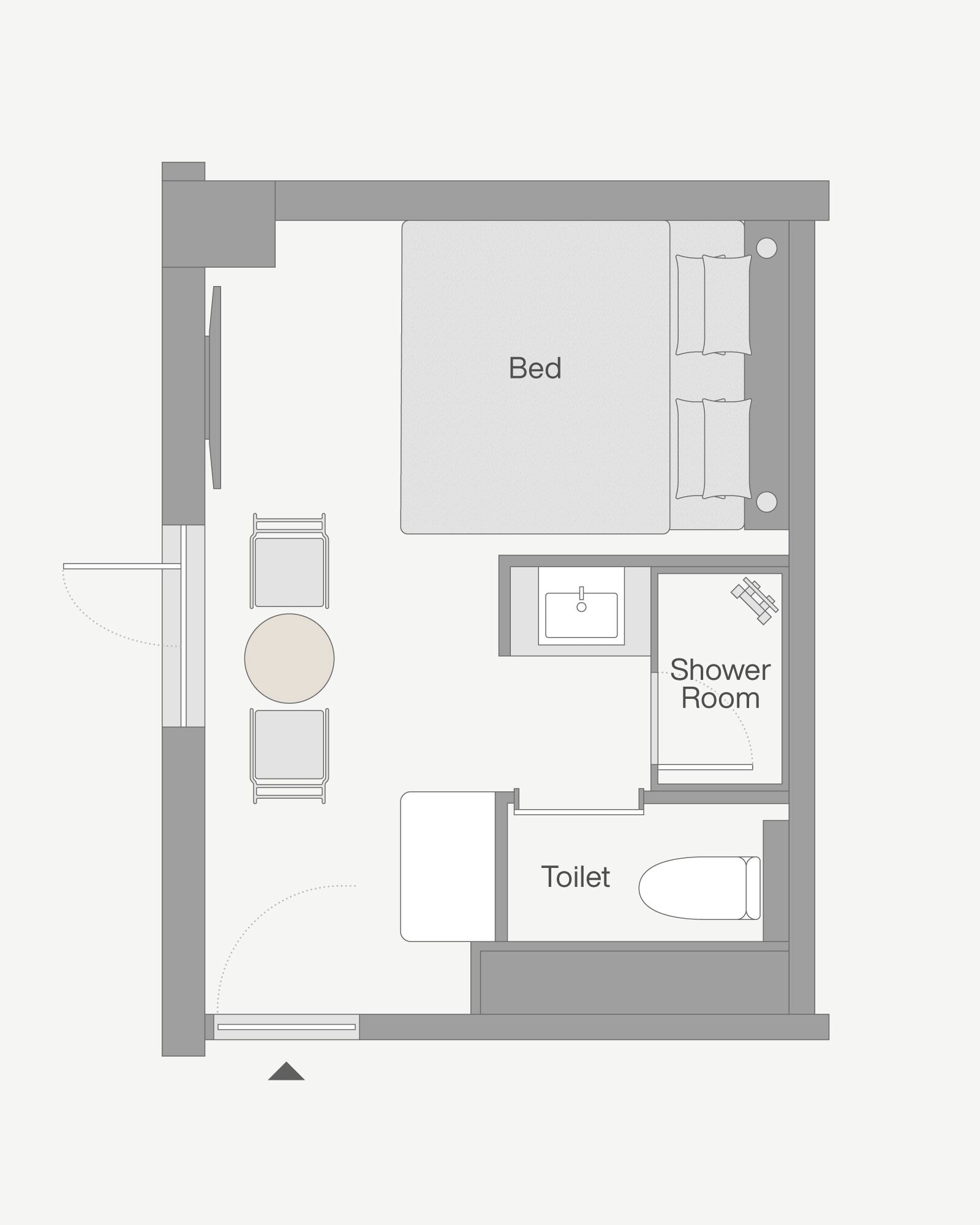 A floor plan of a hotel room with a bed, a shower room, a toilet, and a seating area with a table and chairs.