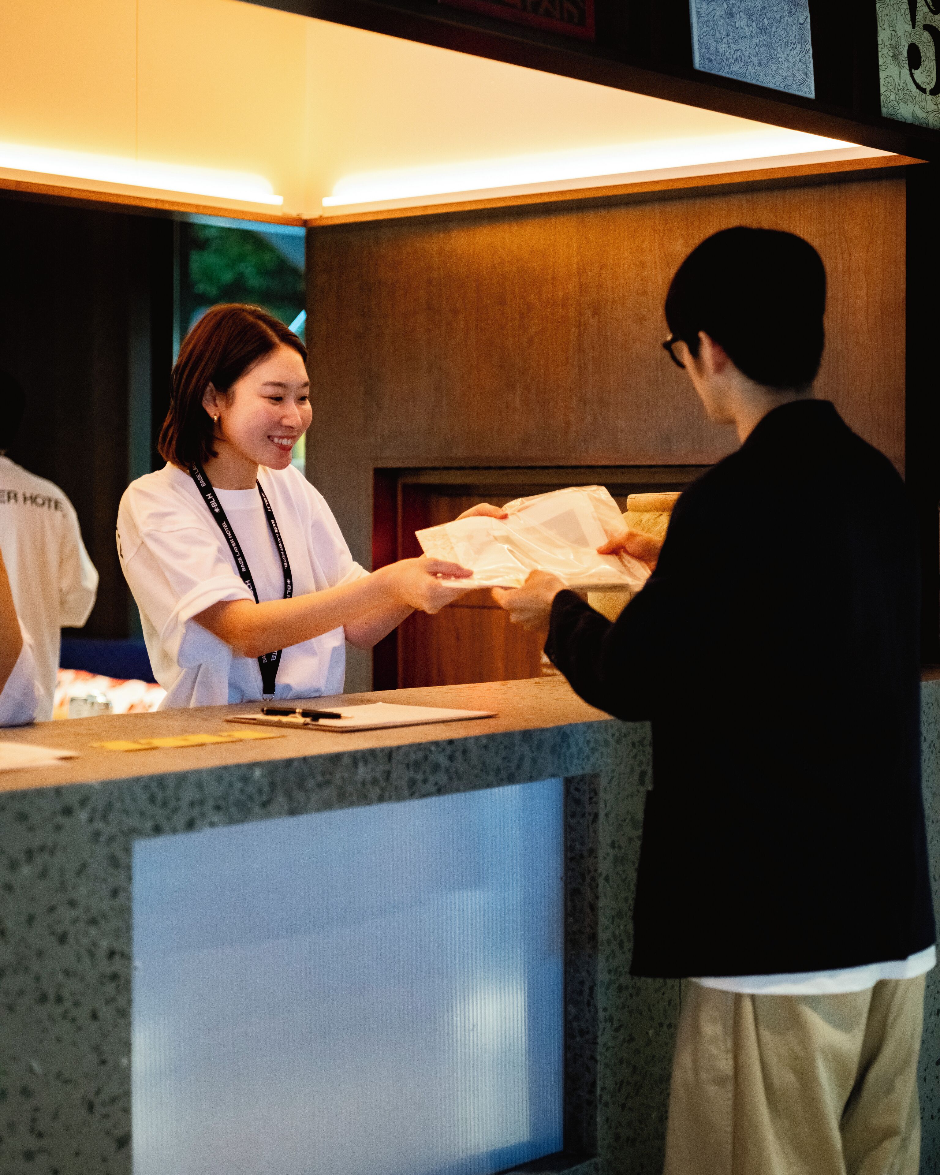 A hotel reception desk with a wooden counter and a digital screen.