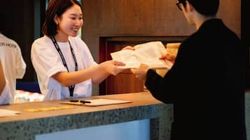 A hotel reception desk with a wooden counter and a digital screen.