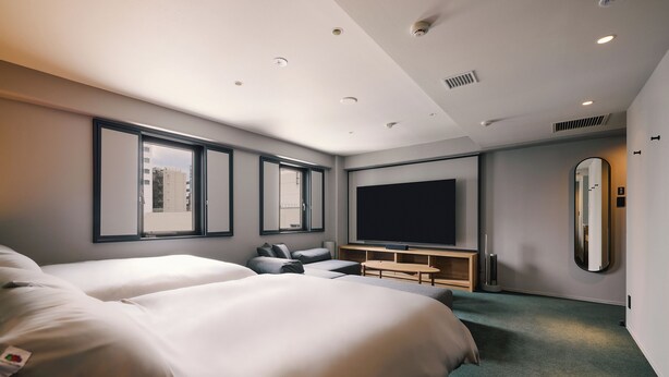 Une chambre d’hôtel moderne dotée de deux grands lits, d’un téléviseur à écran plat, d’un coin salon et d’un grand miroir.