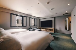 Een moderne hotelkamer met twee tweepersoonsbedden, een flatscreen televisie, een zithoek en een grote spiegel.