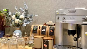 Una estación de café con una máquina de café, dispensadores de té y una variedad de bolsitas de té.