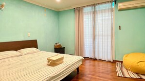Un dormitorio con cama, mesita de noche, ventana con cortinas y unidad de aire acondicionado.