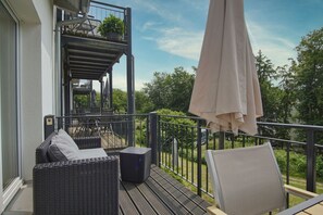 Een balkon met buitenmeubilair, een bloempot en een grote parasol.