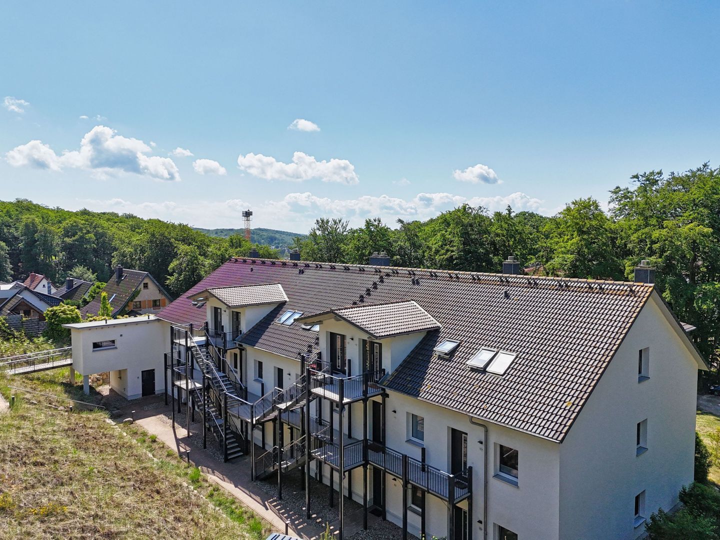 Ein mehrstöckiges Gebäude mit geneigtem Dach, mehreren Balkonen und einer Treppe, die zu den oberen Stockwerken führt.