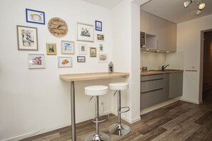 Een moderne keuken met een houten aanrecht en roestvrijstalen apparatuur, een houten wandklok en een reeks ingelijste foto's aan de muur.