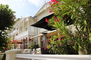 Un hotel con balcones, mobiliario exterior y abundante vegetación.