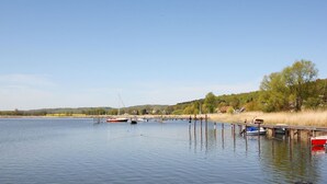 A calm lake with boats docked at wooden piers, surrounded by trees and a clear sky. - Residence Waldidyll FeWo Kleiner Stubber - with use of the swimming pool at AHOI Sellin - (Sellin)