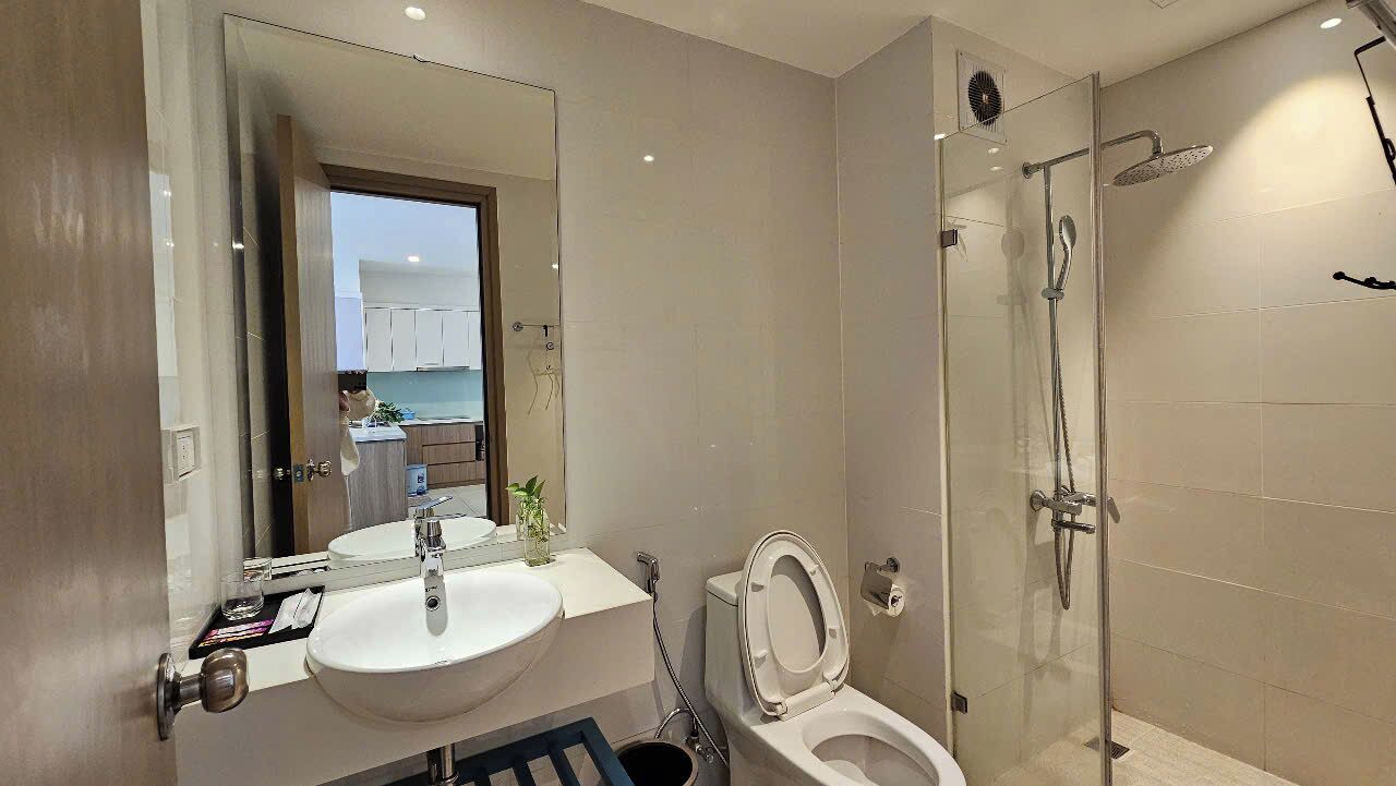 A modern bathroom with a glass-enclosed shower, a white sink, and a toilet.