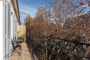 A balcony with a table and chairs, a wooden fence, and a metal railing.