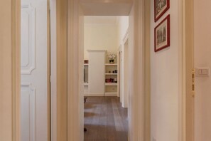 Ein Flur mit weißen Wänden, Holzboden und einem Bücherregal mit Büchern und Dekorationselementen.
