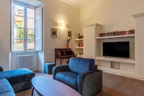 Een woonkamer met een groot raam, een televisie en een boekenkast.