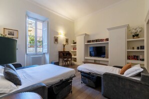 Ett hotellrum med två sängar, ett skrivbord, en TV och bokhyllor.
