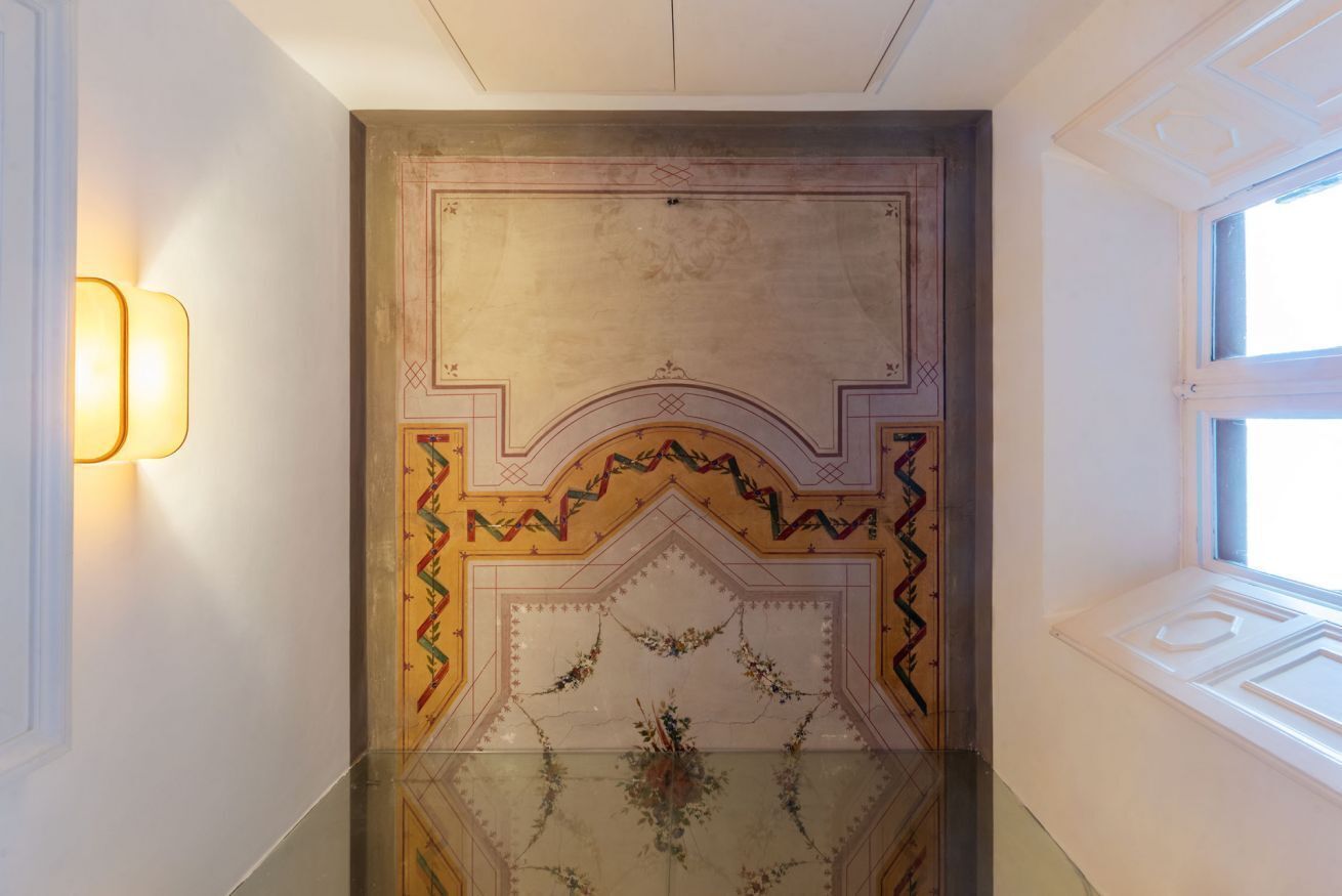 A hallway with a decorative ceiling and a window on the right.