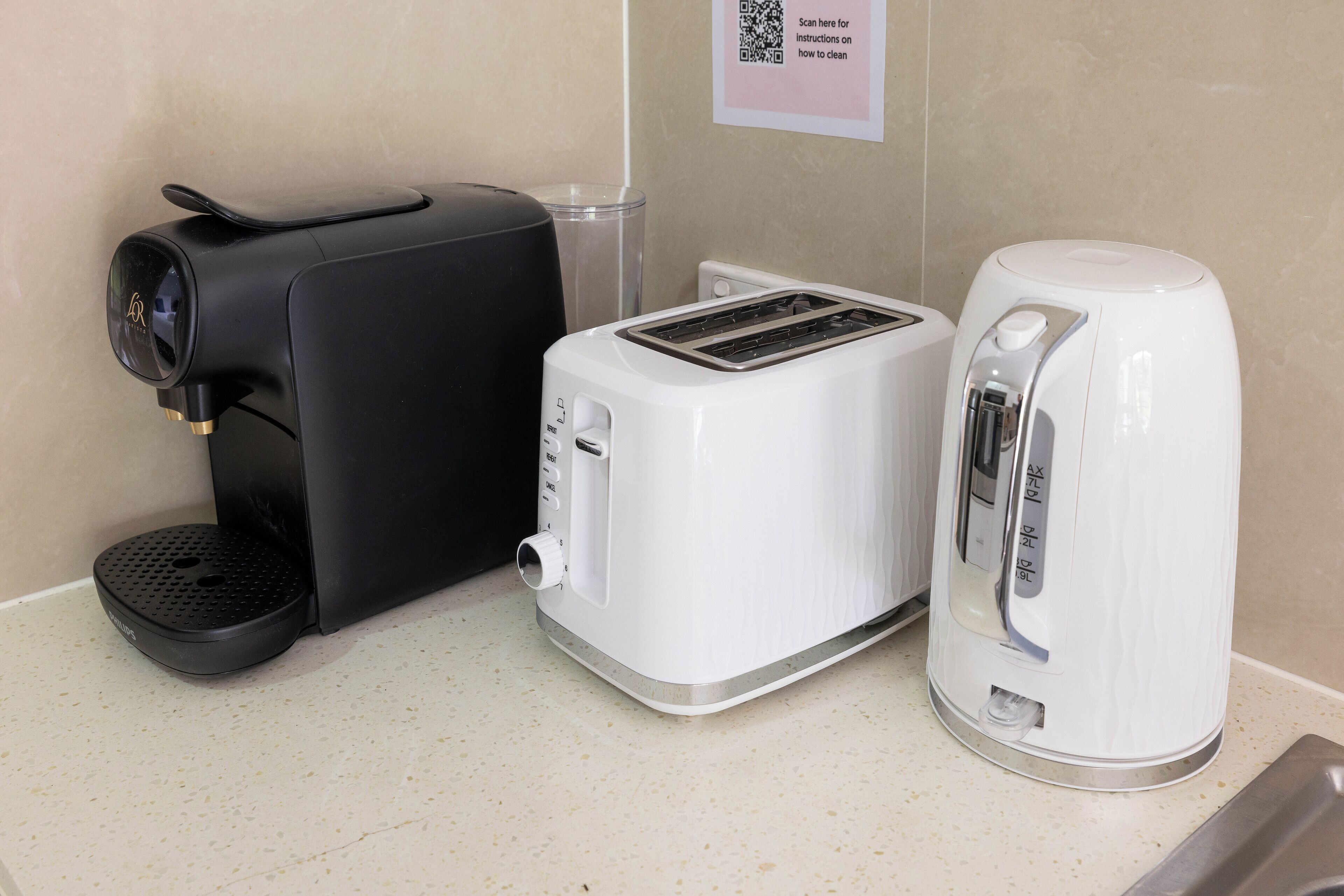 A coffee maker, a toaster, and a kettle on a countertop.