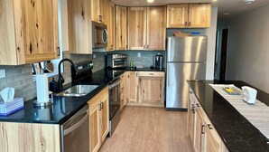 Una cocina moderna con armarios de madera, electrodomésticos de acero inoxidable y una encimera negra.