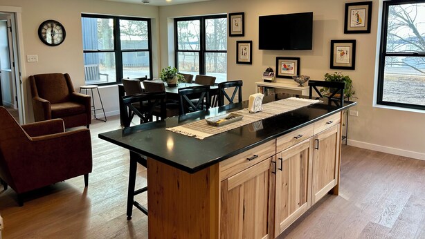 Una cocina moderna con una isla central, armarios de madera y un comedor con sillas y una mesa.