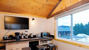 Eine kleine Küche mit großem Fenster, Holzboden und Barhocker.